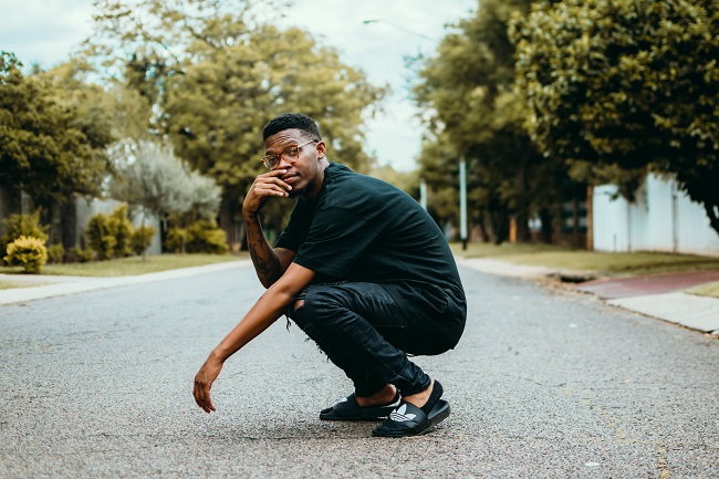 Dans un parc en ville, un jeune adulte est accroupi