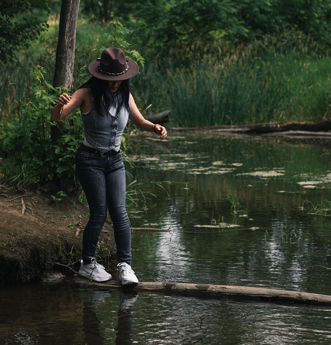 femme traversant une rivière en marchant sur un arbre. Le mouvement, l'environnement et le cerveau collaborent étroitement.