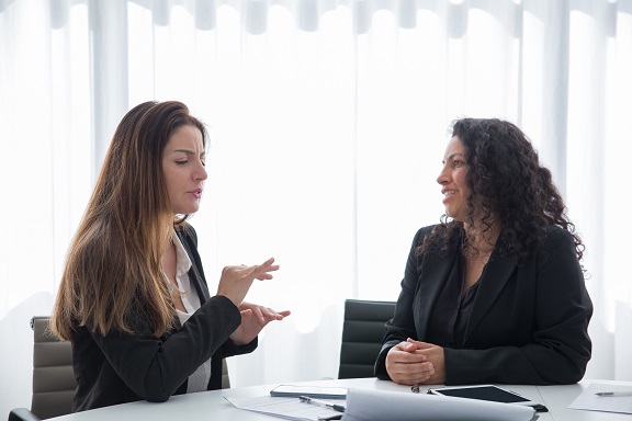 Deux femmes discutent, l'une accompagne naturellement ses paroles avec des gestes des mains.
