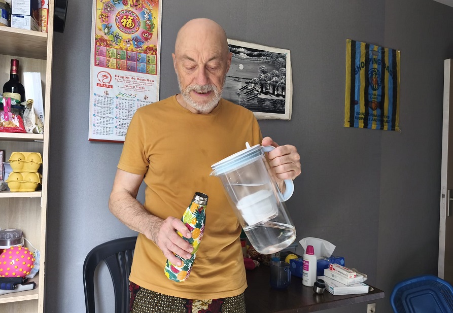 Pierre-Marie remplit une gourde avec sa main gauche