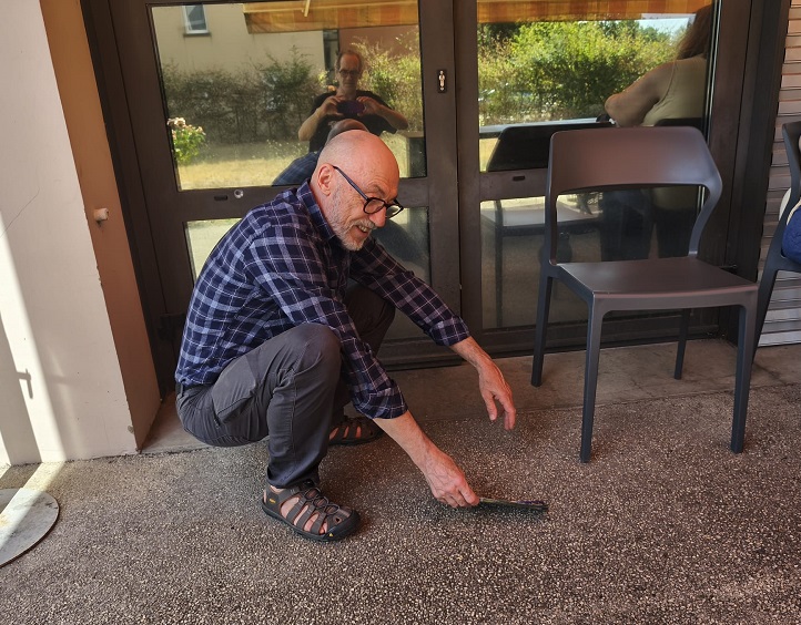 Pierre-Marie accroupi pour ramasser une revue au sol.